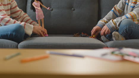 Close-Up-Of-Two-Children-Playing-With-Gender-Specific-Doll-And-Dinosaur-Toys-At-Home